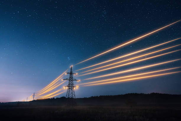 torres de transmissão de eletricidade com fios laranjas brilhando contra o céu noturno. - energy management - fotografias e filmes do acervo