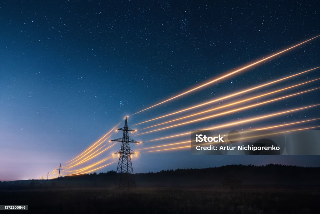 Electricity transmission towers with orange glowing wires against night sky. - Royaltyfri Elektricitet Bildbanksbilder