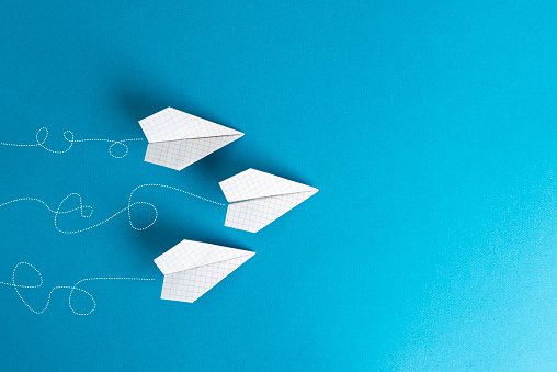 White paper planes in a row on blue background with painted starting effect.