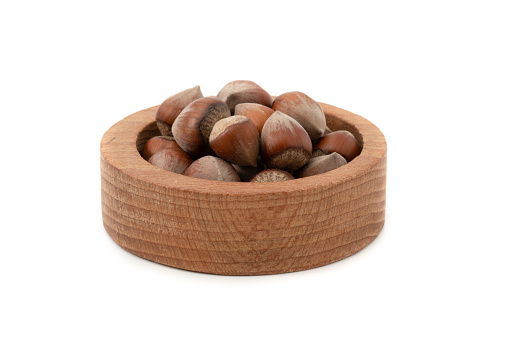 Hazelnuts in wooden bow isolated on white background.