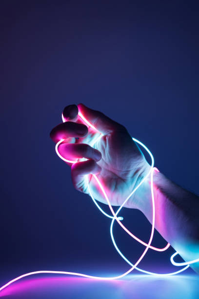 istock Hand tied with neon led cables on a dark background. 1372204508