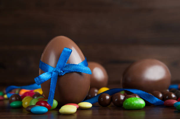 Easter composition with delicious sweets, chocolate eggs and blue bow on wooden background, space for text