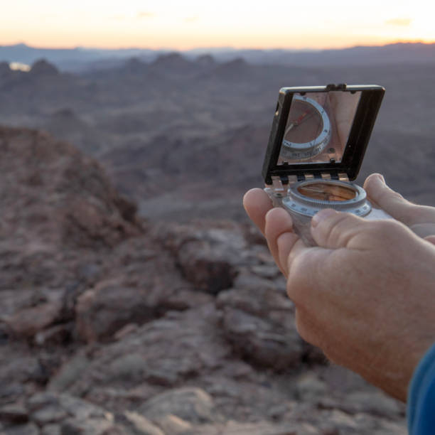 istock Hiker looks at compass for directions, from trail 1372208393