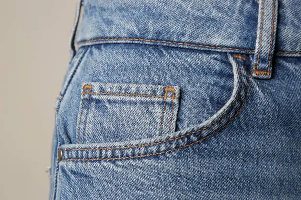 Tiny front pocket on denim pants, close up.