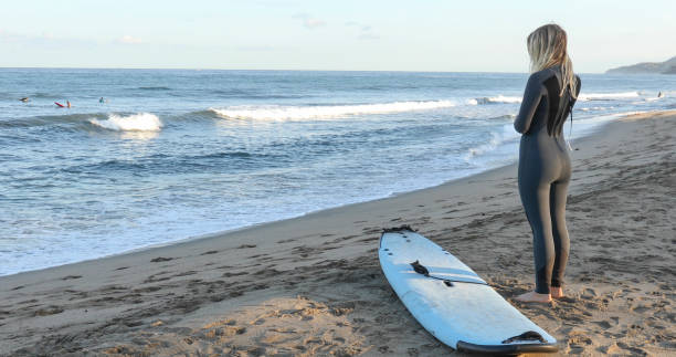 istock Young woman gets ready for a morning surf 1372208521