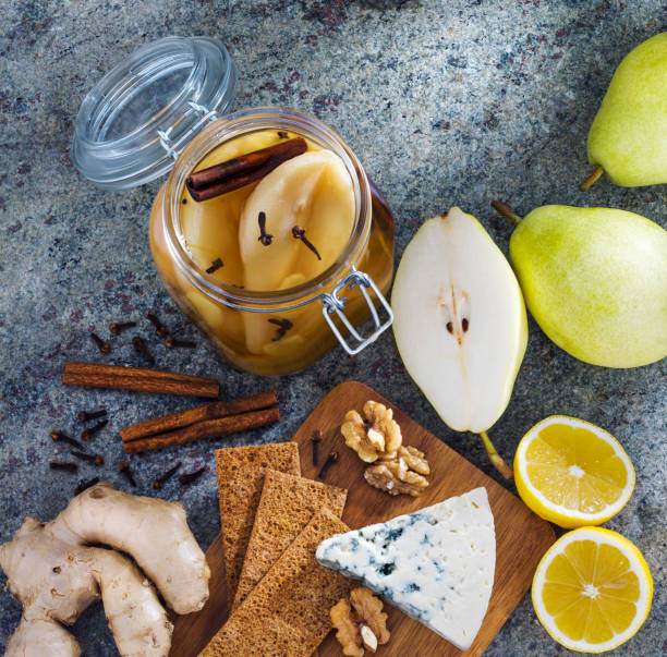 Homemade ginger pear jam preparation in jar with lemon, roquefort cheese, clove, walnuts and cinnamon.