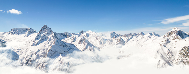 Panorama of mountains above the clouds under a clear sky on a sunny day . High quality photo