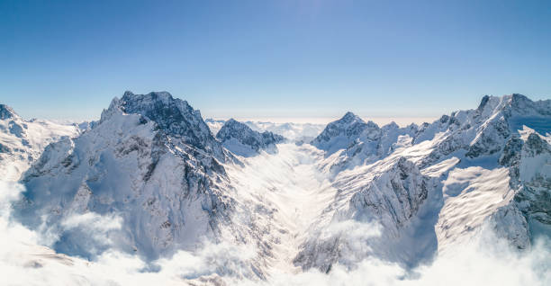 istock Mountain peaks shine under the sun above the clouds 1372208890