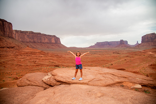 Famous place. Usa. Utah. Happiness. Vacation. Happy little girl with open arms embrace the Monument Valley.
