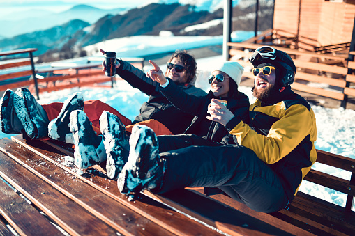 Friends Pointing Towards Ski Center On Top Of Mountain While Enjoying Coffee Near Cabin