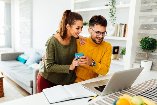 Caucasian couple working from home using a laptop stock photo