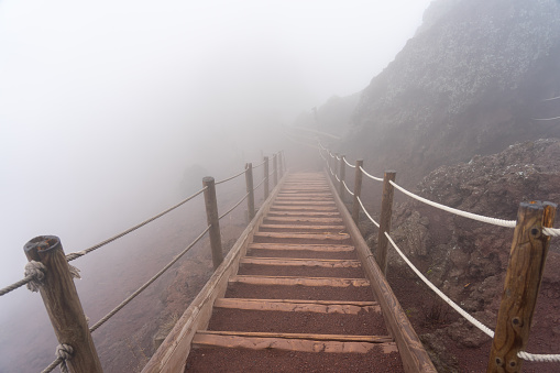wooden stairs on a foggy day on the pedestrian path to the top of the mount vesuvio volcano.  Naples, Italy.