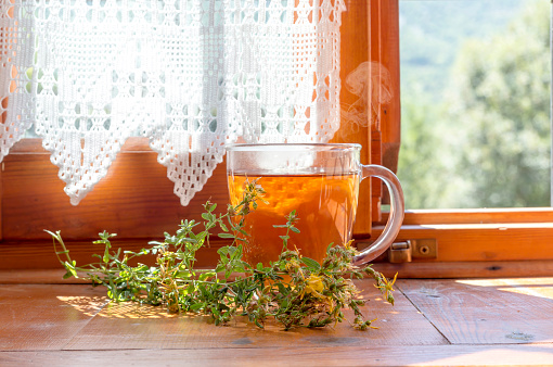 Herbal, hot tea in a glass cup made from herbs (Hypericum) on rustic window close-up