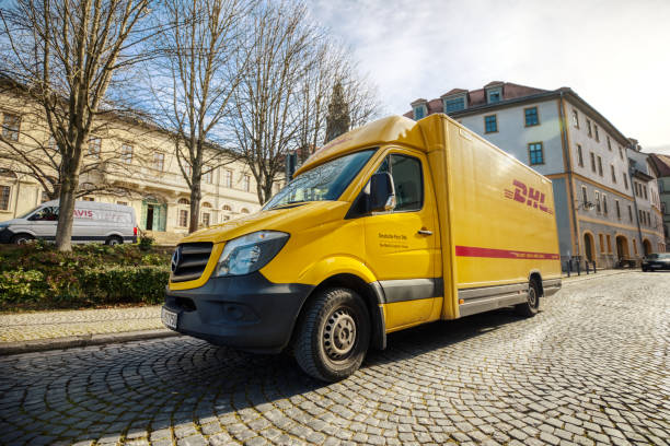 il furgone tedesco per pacchi di dhl si trova in una zona pedonale per caricare i pacchi - deutsche post ag package germany occupation foto e immagini stock