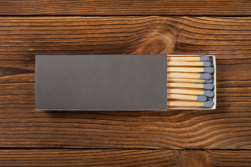top view grey color matchbox with grey match sticks on a wood table