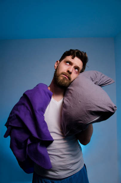 istock Miserable man with blanket and pillow after sleepless night 1372232552