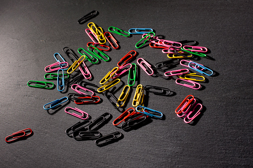 colored paper clips on a dark background. High quality photo