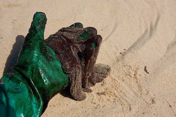 A worker's hand wearing a green protective glove picks up a \