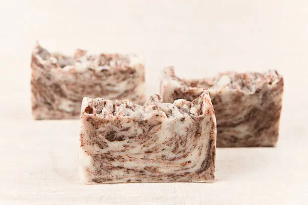 Bars of natural handmade chocolate soap on a linen fabric.