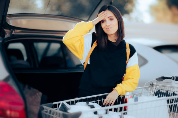 Forgetful Woman Putting the Shopping Bad in the Cart Trunk Funny customer having regrets for buying so much after leaving the supermarket consumer confidence photos stock pictures, royalty-free photos & images