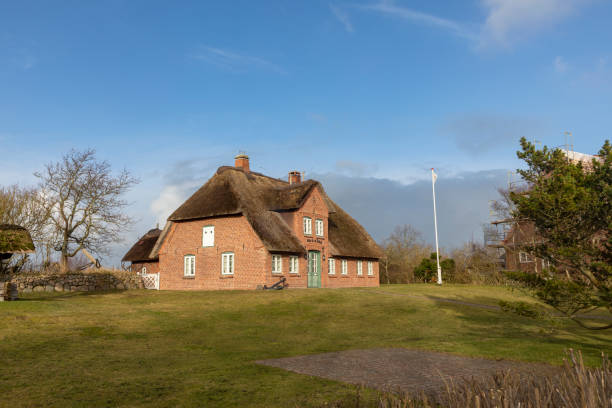 typical red brick frisian house with thatched roof on sylt island in list village, germany. - thatched roof red brick roof imagens e fotografias de stock