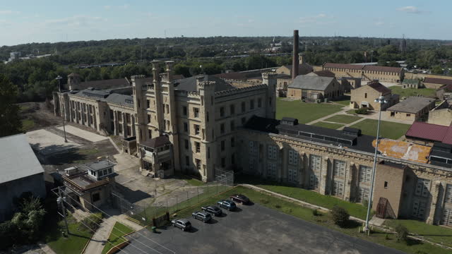 Aerial view of the old and abandoned Joliet prison or jail, a historic site. Drone slowly flying up to capture wide view of the Joliet prison. Streets of Naperville Illinois and Joliet Prison.