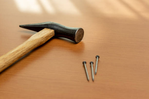 istock Three iron nails and a hammer on the wooden board by the window 1372259618