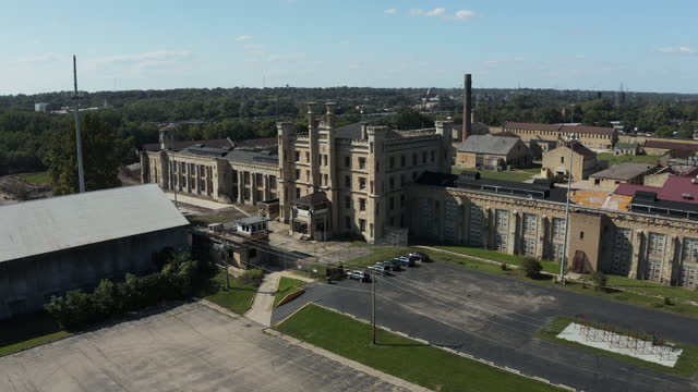 Aerial view of the old and abandoned Joliet prison or jail, a historic site. Drone flying up from a distance to capture panoramic view of the area. Streets of Naperville Illinois and Joliet Prision.