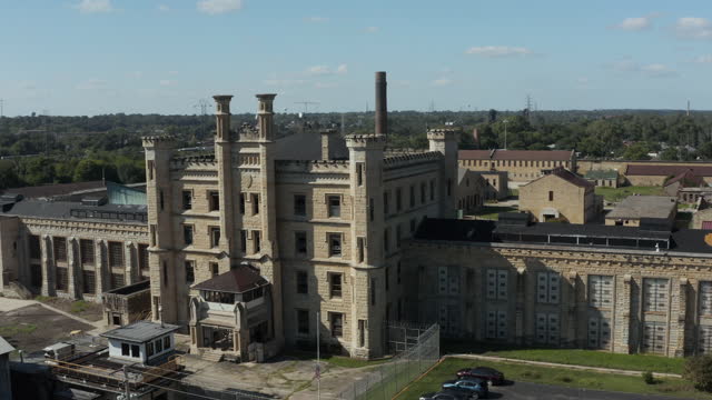 Aerial view of the old and abandoned Joliet prison or jail, a historic site since 1880s. Drone rotating to capture view of front gate. Streets of Naperville Illinois and Joliet Prison.