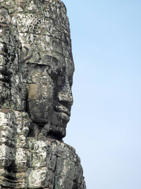 Stone face carving at Bayon temple Close-up of the profile of a large face carved in stone at the famous Bayon temple, Angkor Wat, Siem Reap, in Cambodia. Face is set to the left of frame, blue sky background to the right. khmer stock pictures, royalty-free photos & images