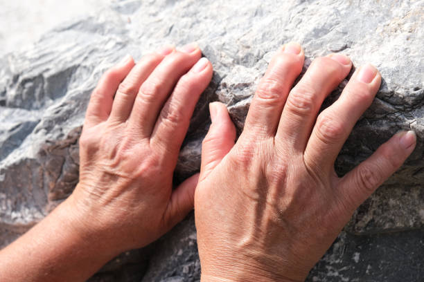 close up hands of senior woman on stone background. arthritis, osteoporosis, rheumatism - thumb stones imagens e fotografias de stock
