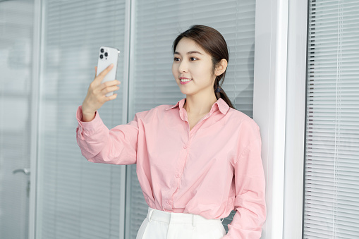 A beautiful Asian business woman is looking at her smartphone and very happy