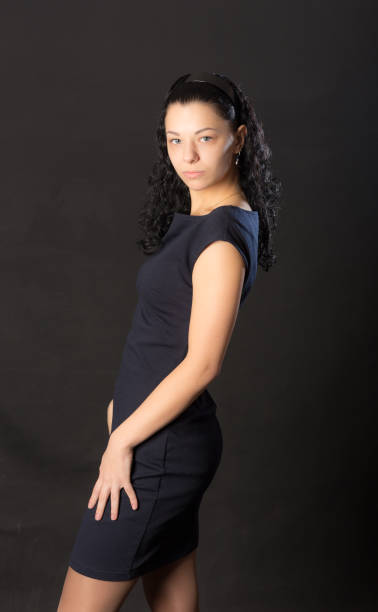 portrait of beautiful young black woman with curly hair posing at gray background