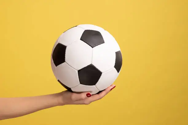 Photo of Woman hand holding football or soccer ball, supporting favorite football team on match.