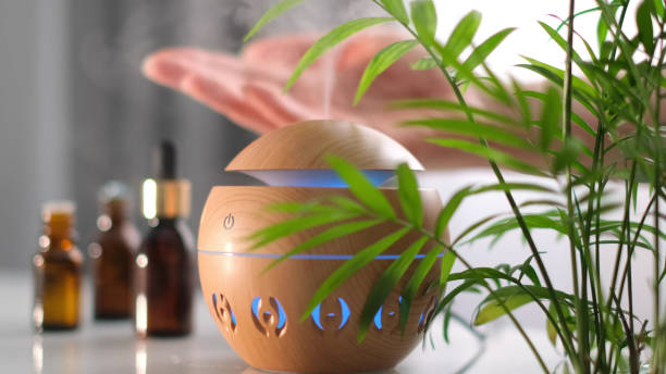 Modern aroma oil diffuser on the white table. Spa concept for body and health care. female is adding essential oil to an aroma diffuser stock photo