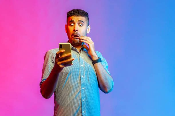 istock Man looking at smartphone display with funny scared face, shocked and surprised with application. 1372288341