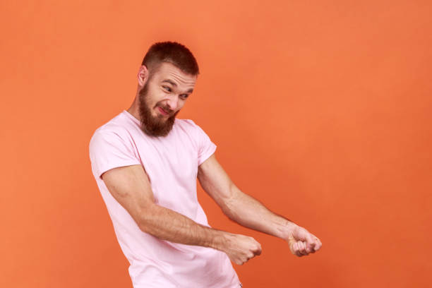 istock Man keeping fists up, holding invisible virtual rope and pulling object, striving hard with effort. 1372288457