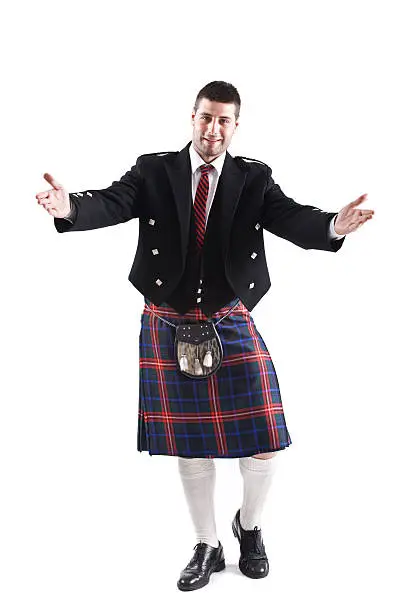 Handsome young Scotsman wearing traditional uniform, posing. Full body shot isolated on white background
