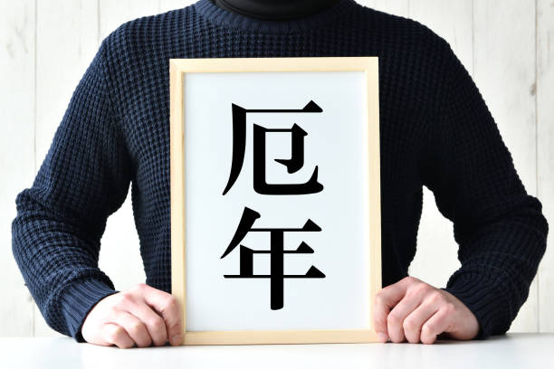 「不運な年」という言葉が日本語で書かれているボードを持つ日本人男性 - human age ストックフォトと画像