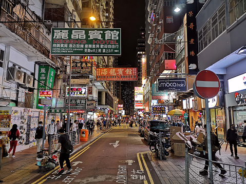 People walking on a street in Mongkok district by night, Kowloon Peninsula.  The area, with its extremely high population density of 130,000/km2 was described as the busiest district in the world. Hong Kong