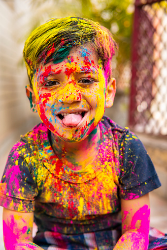 Portrait of cute happy Indian little boy covered with colored powder and celebrating the Holi festival.