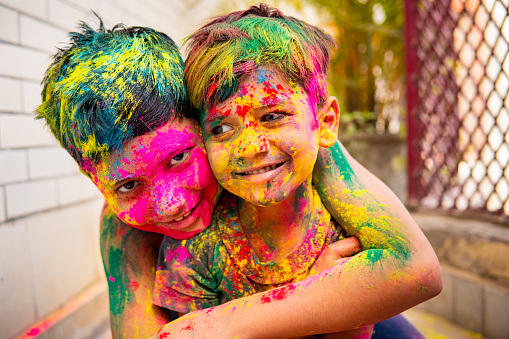 Two happy Indian brothers celebrating Holi festival of colors and having fun together.