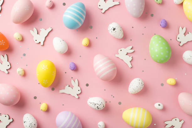 istock Top view photo of easter decorations glowing confetti white easter bunnies and multicolored eggs on isolated pastel pink background 1372291677