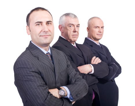 Waist up shot of three mature businessmen looking at camera with their arms crossed
