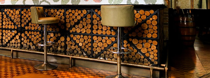 Leather bar stools at lounge counter decorated with wood log slices and black metal frame