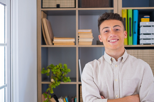 Portrait of one young and happy cheerful man smiling looking at the camera having fun. Headshot of male person working at home in the office.