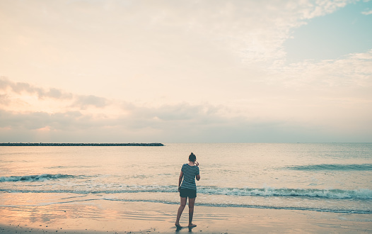 Rear view of woman walking alone on the seaside. Tropical landscape summer sea concept.