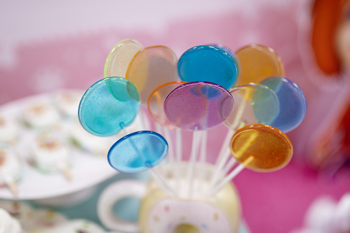 blue, yellow, orange, light green, blue lollipops on a stick on a blurred background
