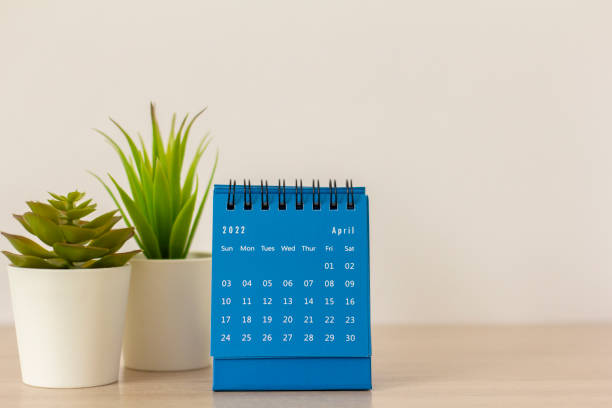istock Desktop blue calendar for April 2022 on the table. 1372303474