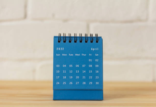 istock Desktop blue calendar for April 2022 on the table. 1372303706
